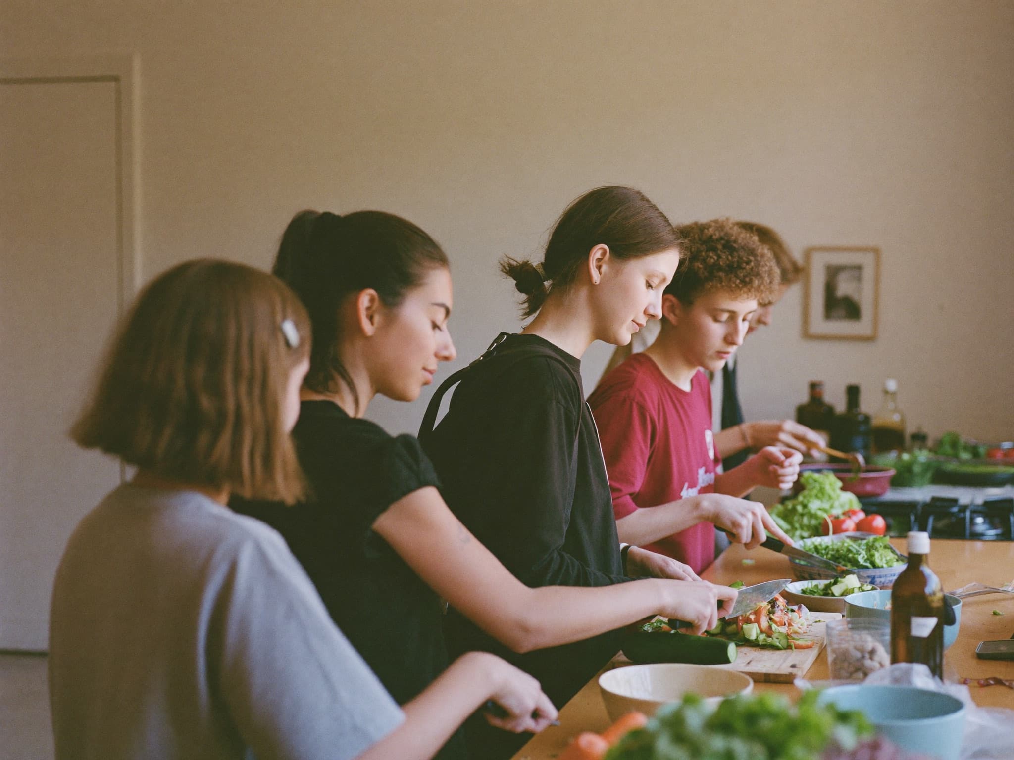 Begeleider en jongeren koken samen in de keuken