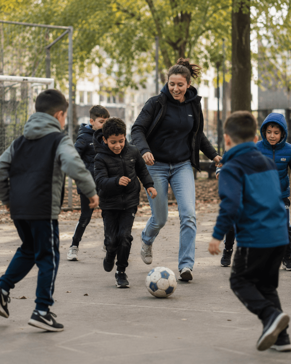 Begeleider voetbalt samen met een groep jongeren